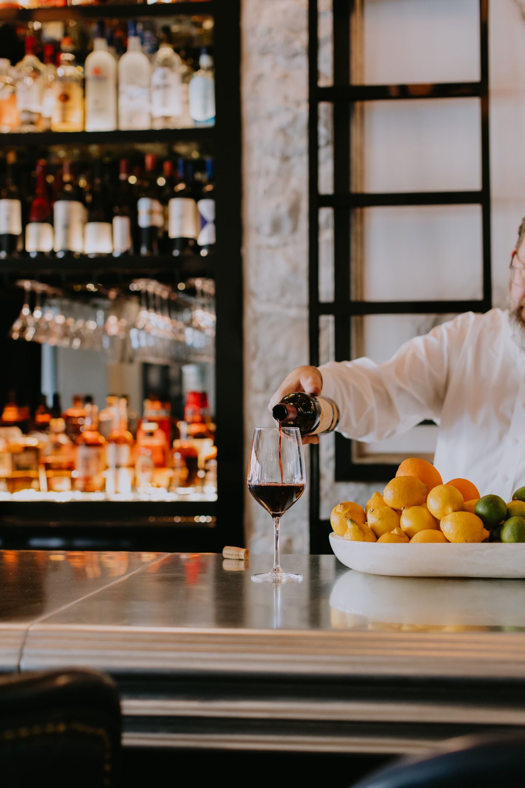 Hand pouring wine on a cast metal zinc bar top at Jojo's